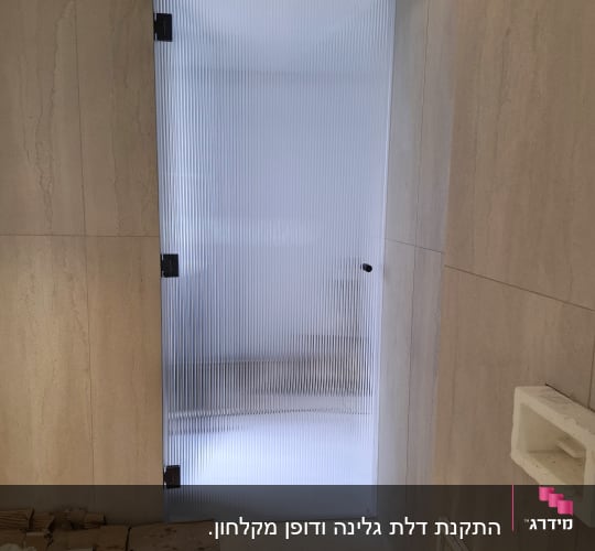 דלת זכוכית מחוספסת במקלחת עם קירות אבן